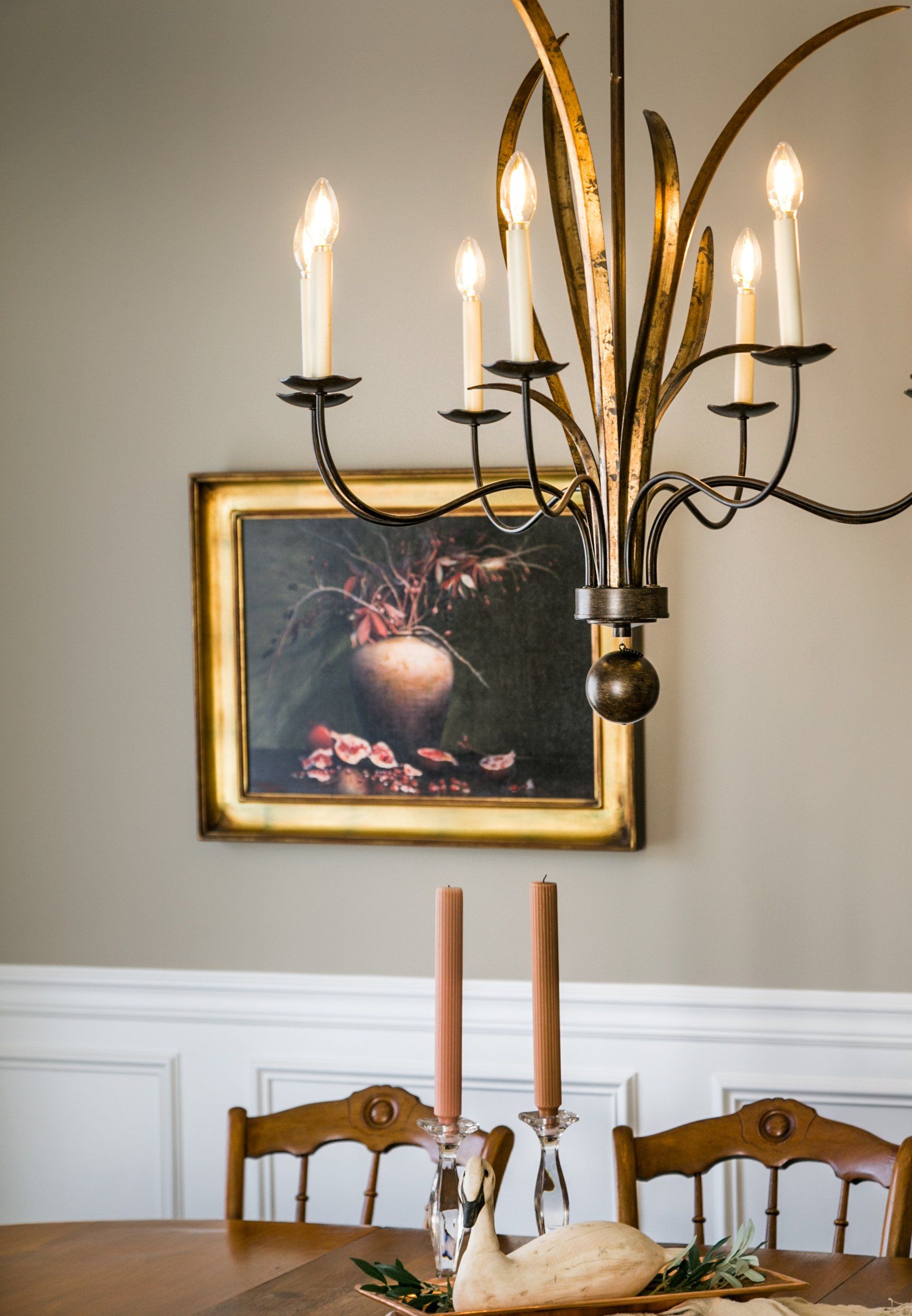 A dining room with a chandelier and a painting on the wall