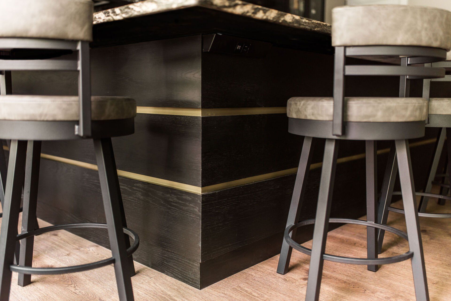 Three bar stools are sitting next to a bar in a kitchen.
