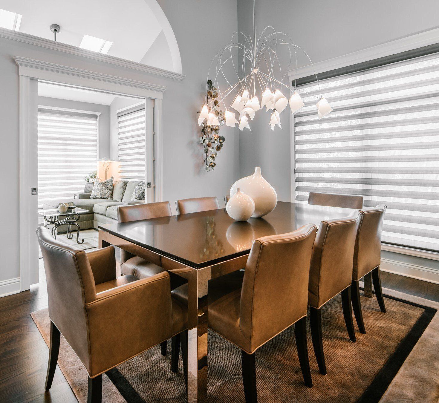 A dining room with a table and chairs and a chandelier hanging from the ceiling.