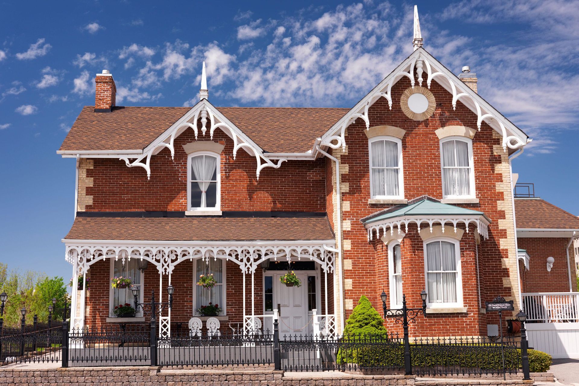 A large brick house with a porch and a blue sky in the background