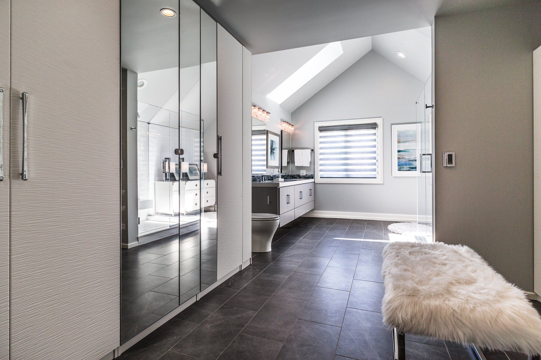A walk in closet with lots of mirrors and a bench.