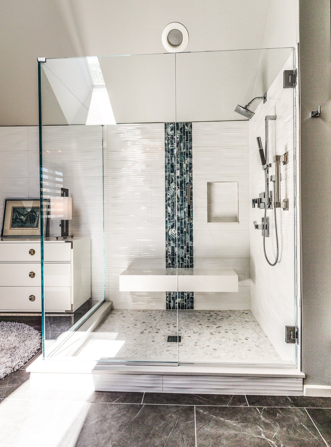 A bathroom with a walk in shower with a glass door