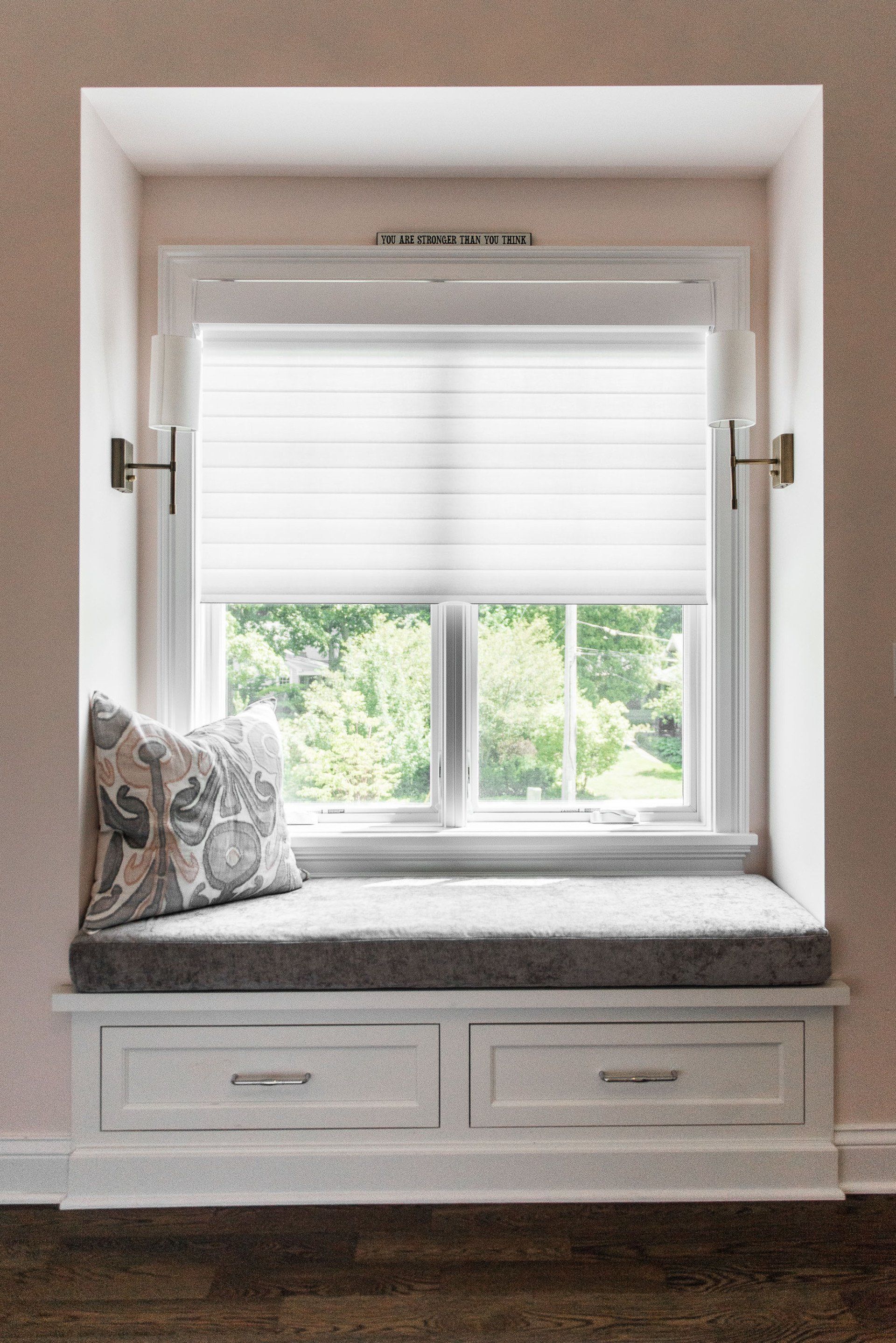 A window seat with a pillow and drawers underneath it.