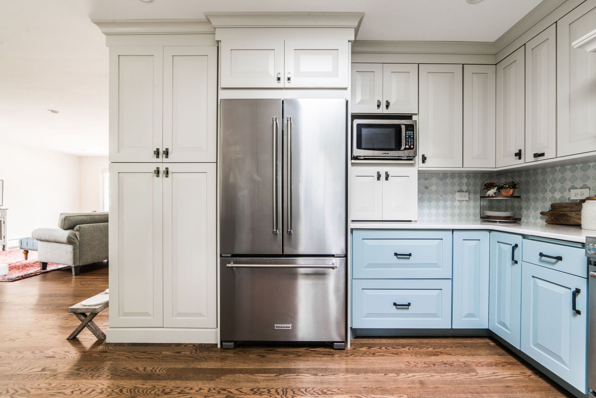 A kitchen with blue cabinets and a stainless steel refrigerator.
