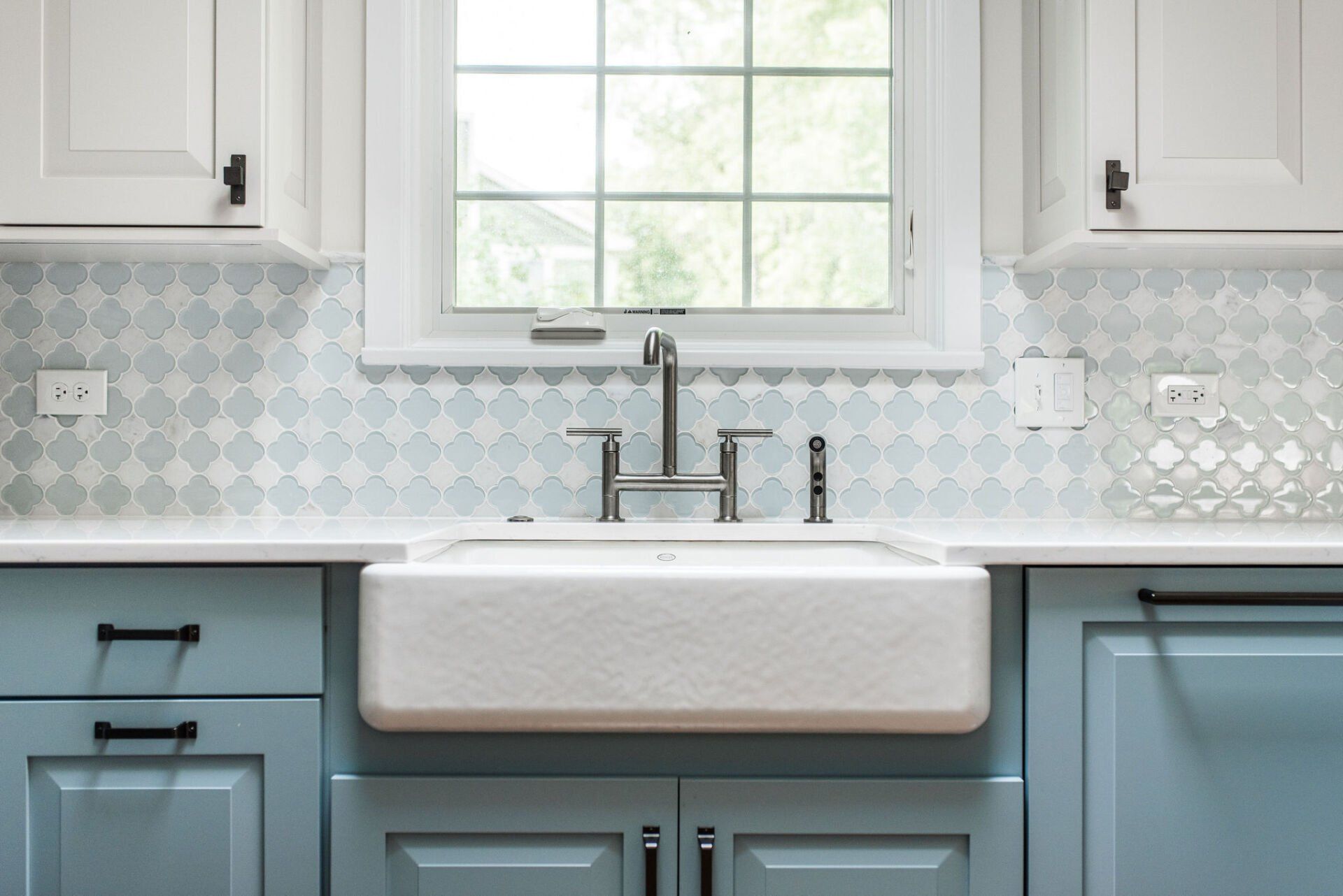 A kitchen with blue cabinets and a white sink under a window.