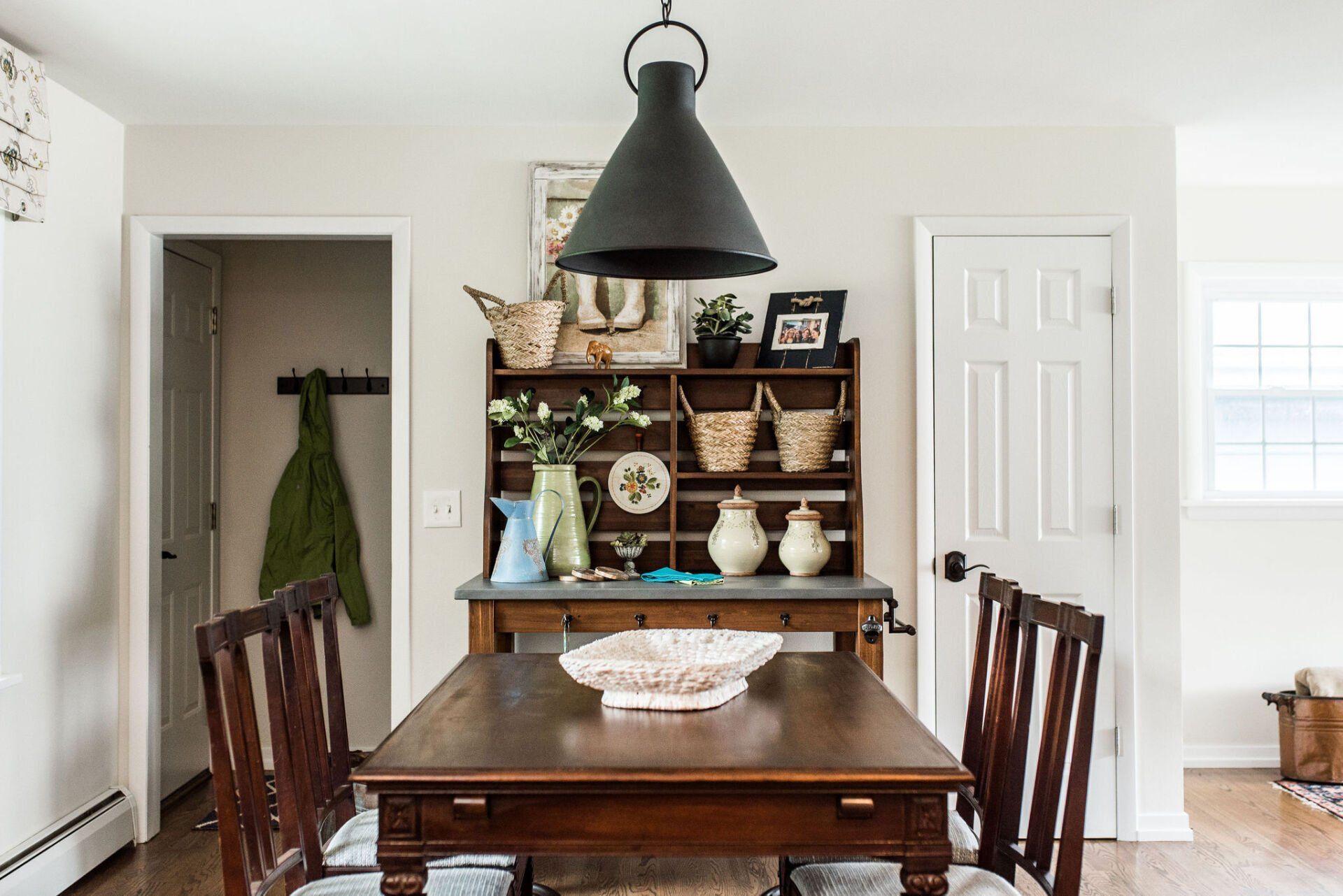 A dining room with a wooden table and chairs and a hutch.