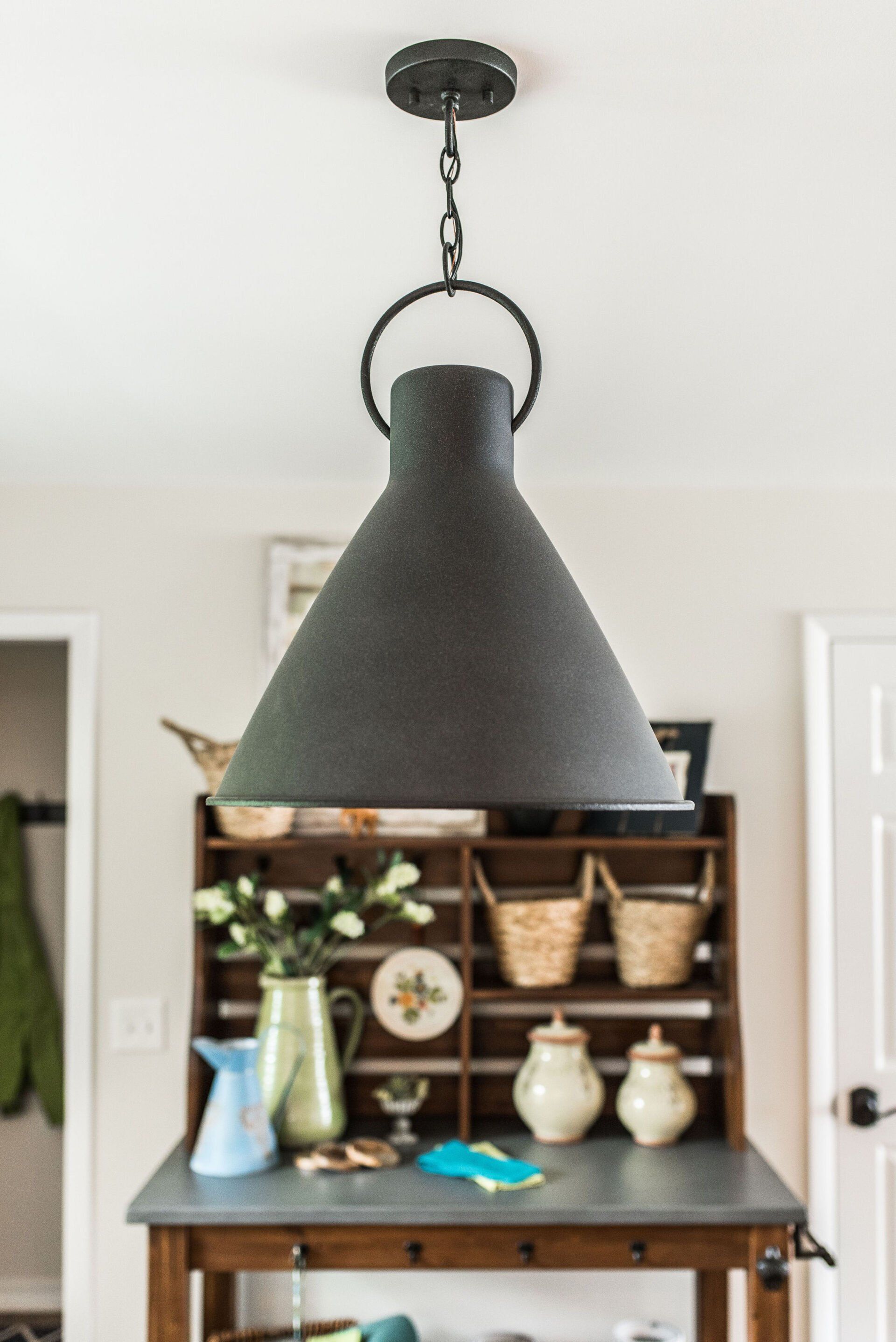 A black lamp hanging from the ceiling above a table