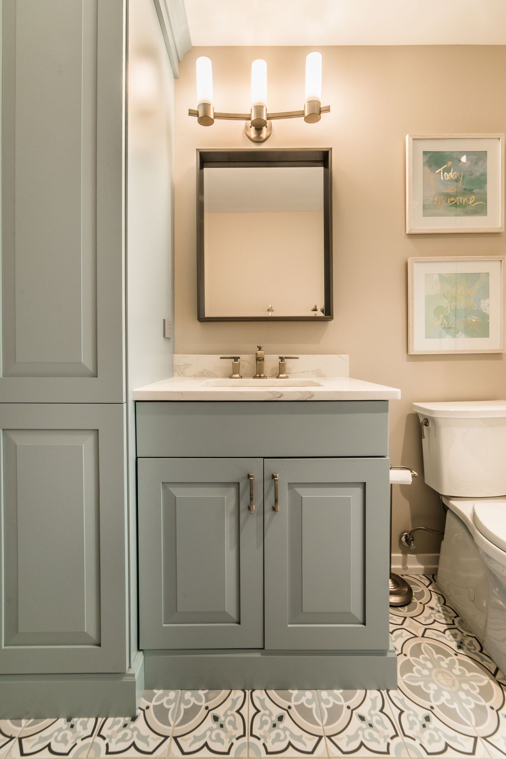 A bathroom with a sink , toilet , mirror and cabinets.
