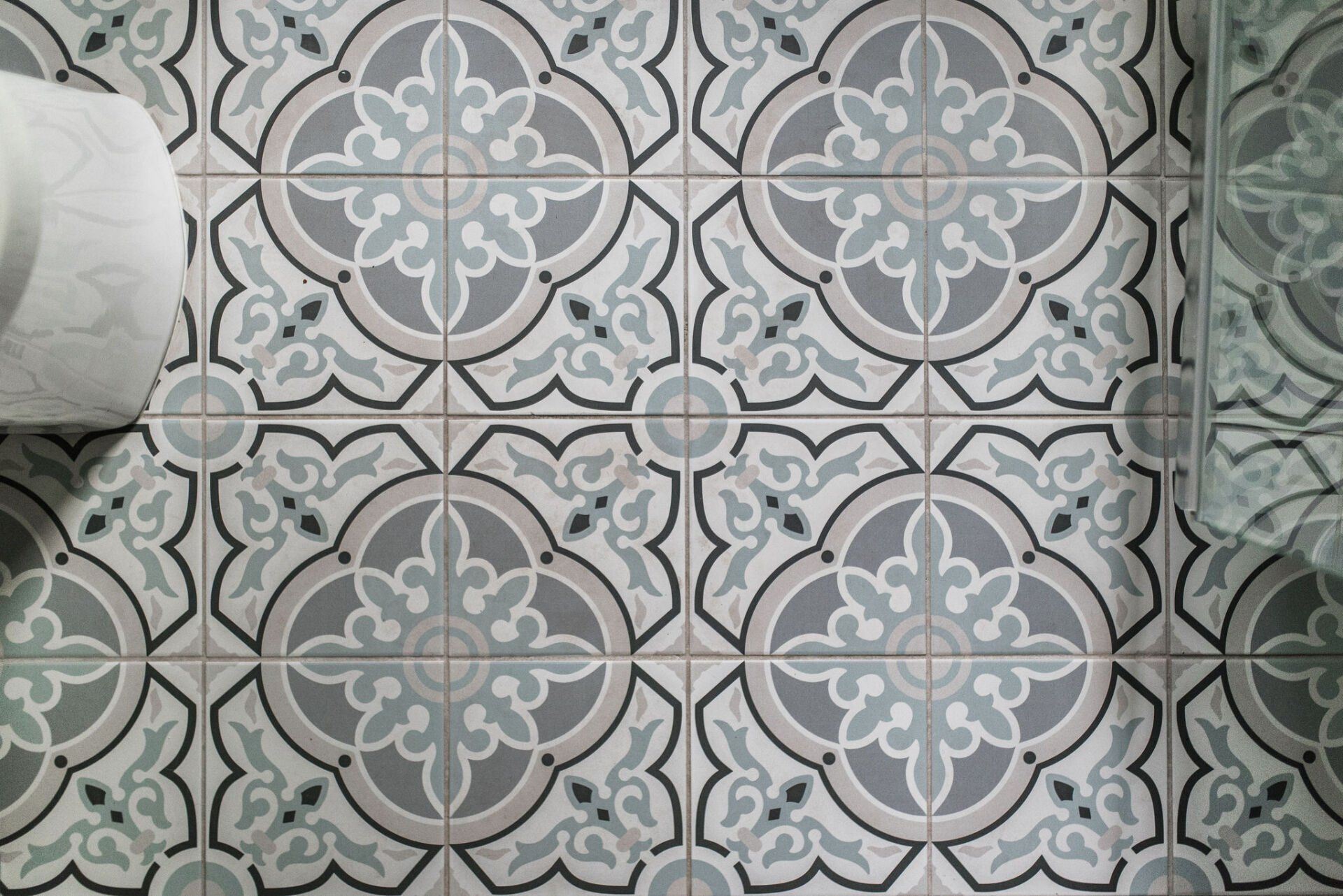A bathroom floor with a patterned tile and a toilet paper roll.