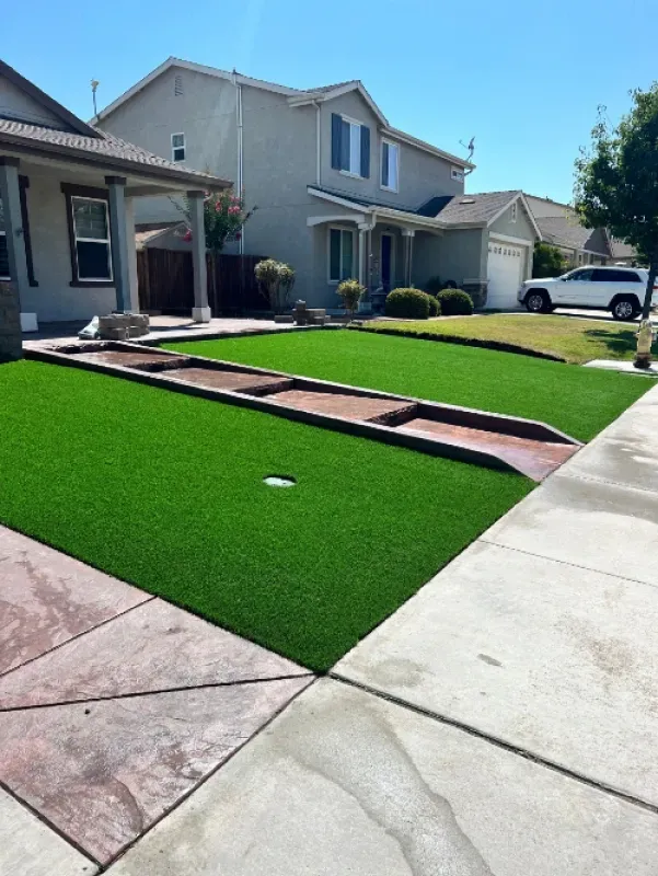 Suburban house with artificial turf lawn, brick edging, and a driveway in front