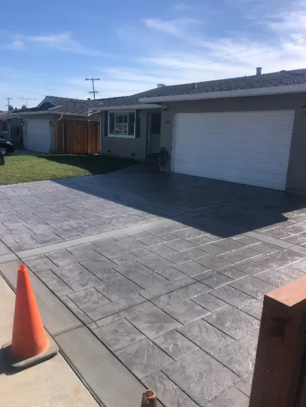 Suburban house with a stamped concrete driveway, white garage door, and orange traffic cone in front