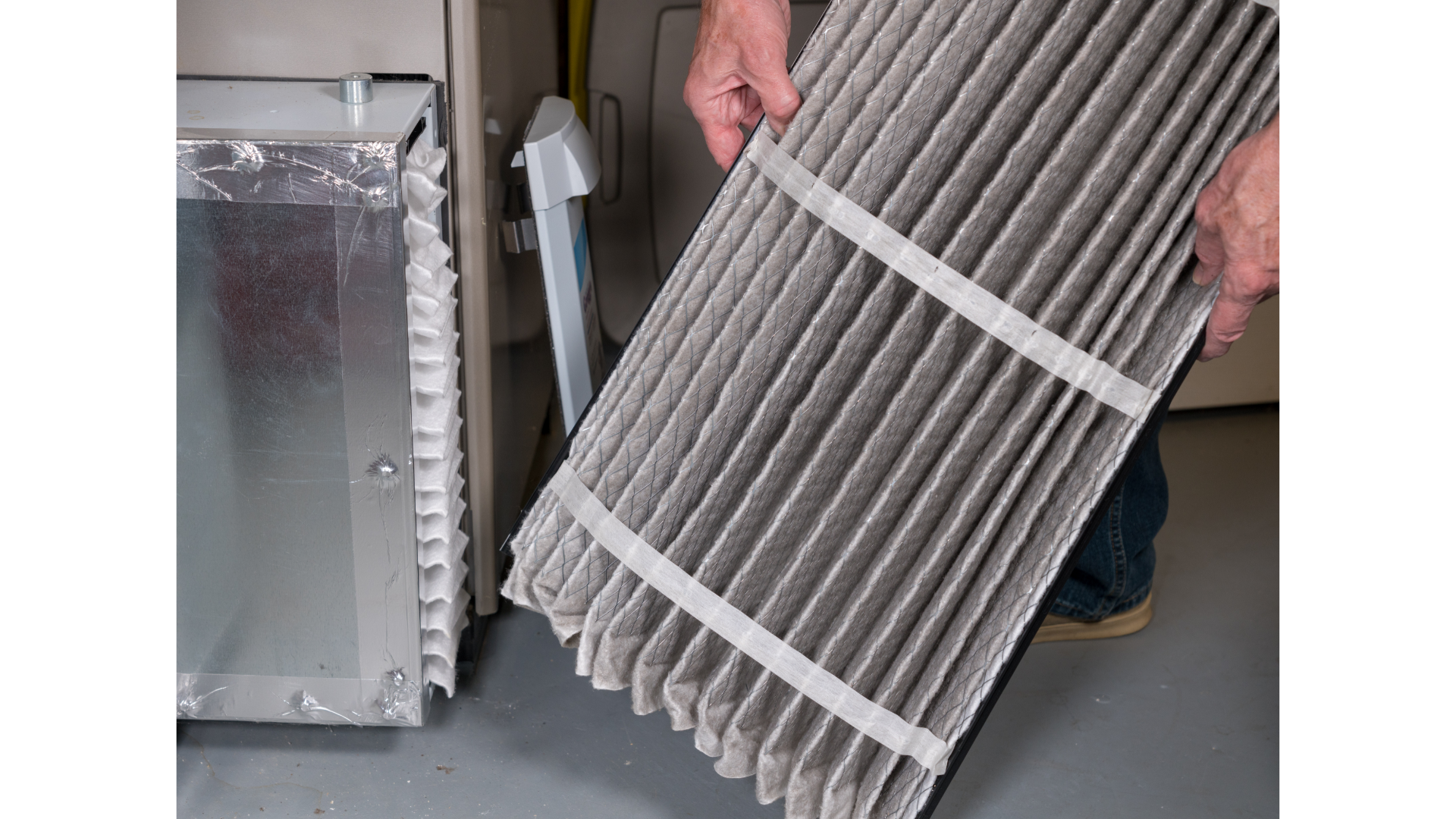 a person is holding a dirty air filter in front of a furnace .