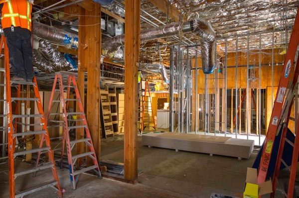 Construction site interior with ladders, wooden beams, and exposed framing under renovation