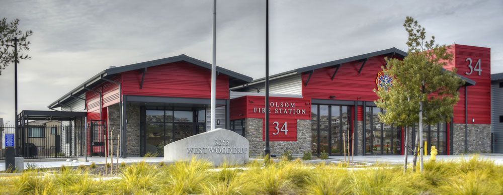 Modern red-and-black building with large windows and a landscaped foreground