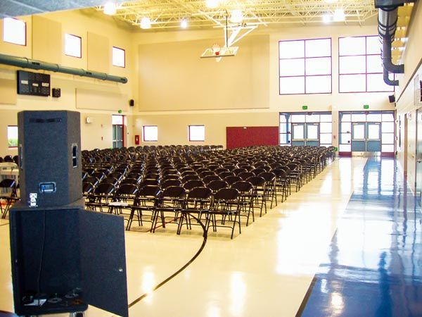 Empty gymnasium with rows of folding chairs set up for an event
