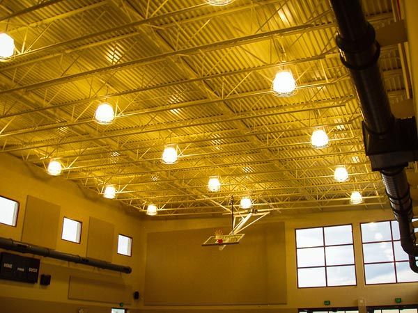 Interior of a gymnasium with bright overhead lights and large windows near the ceiling