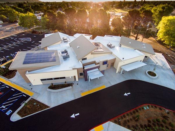 Aerial view of a modern building complex with solar panels and curved driveways at sunset