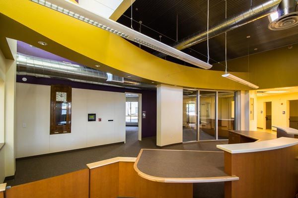 Empty modern office lobby with wood reception desk, glass walls, and exposed ceiling beams