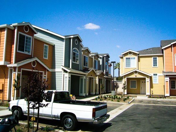Townhouses with a white pickup truck parked along a suburban apartment complex driveway.