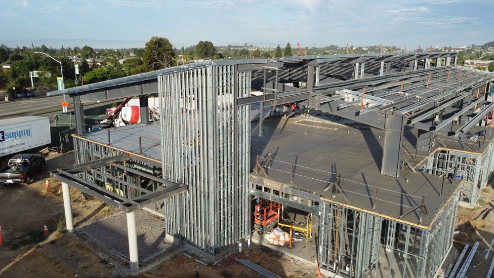 Steel-framed building under construction with scaffolding and cranes on a site outdoors