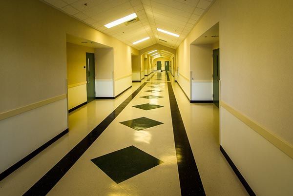 Long, empty yellow hallway with black floor diamonds and doors on both sides