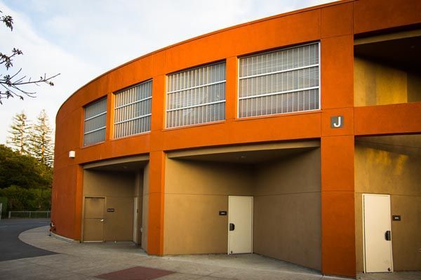 Orange industrial building with tall garage doors and upper windows at dusk