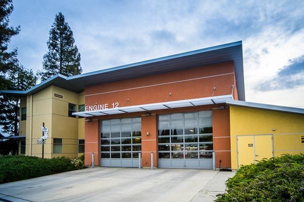 Modern building entrance with orange and yellow walls, large glass doors, and a sloped roof