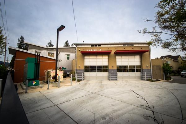 Fire station yard with two garage bays, concrete courtyard, and a tall light pole