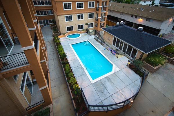Courtyard pool with blue water between apartment buildings and a tiled deck