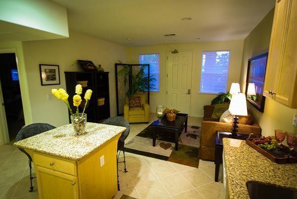 Bright living room with a yellow island, sofa, coffee table, lamp, and a vase of yellow flowers.
