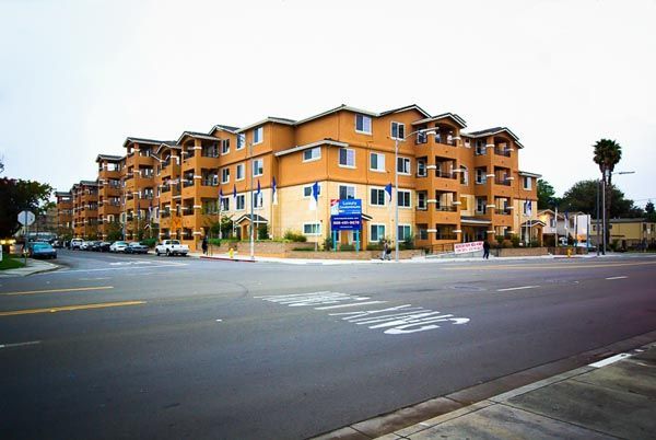 Orange apartment building on a city street corner with a blue sign and empty intersection