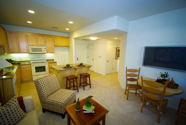 Open-plan apartment with kitchen, dining nook, couch, and wall-mounted TV