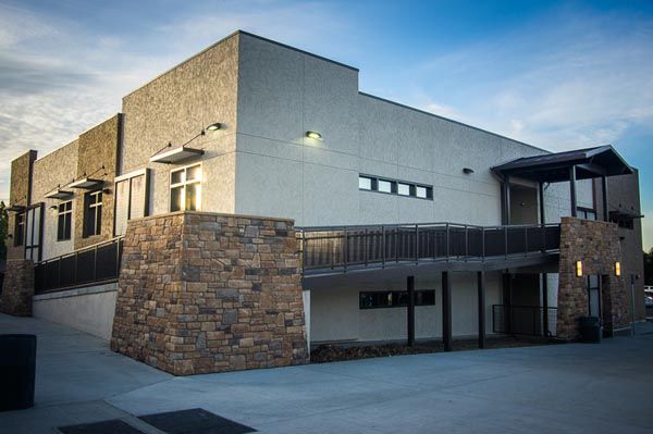 Modern brick-and-stucco building exterior with a covered entrance and parking area