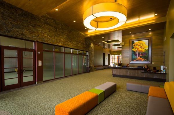 Modern hotel lobby with green carpet, orange benches, and warm ceiling lights