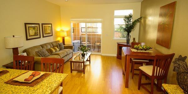 Bright living and dining room with sofa, table, chairs, lamp, and sliding glass doors