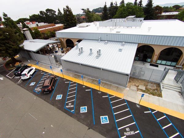 Aerial view of a white building with several accessible parking spaces marked in blue and black.