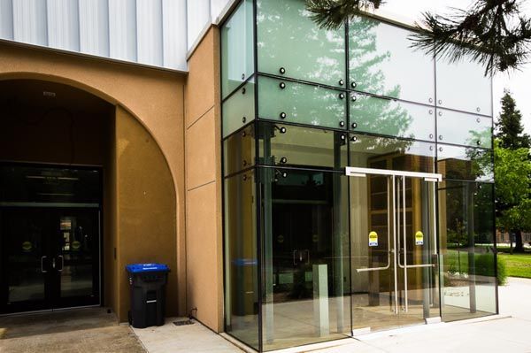 Glass-fronted building entrance with a tan archway and double glass doors