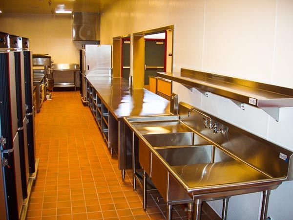 Commercial kitchen with stainless steel sinks and orange tile floor
