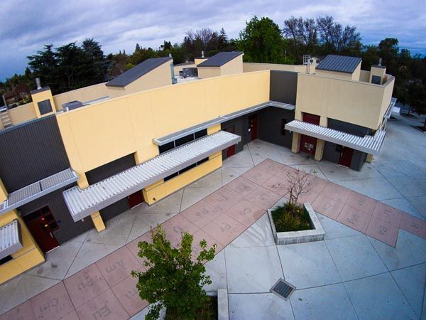 Courtyard view of a yellow apartment complex with walkways and a small planter at center