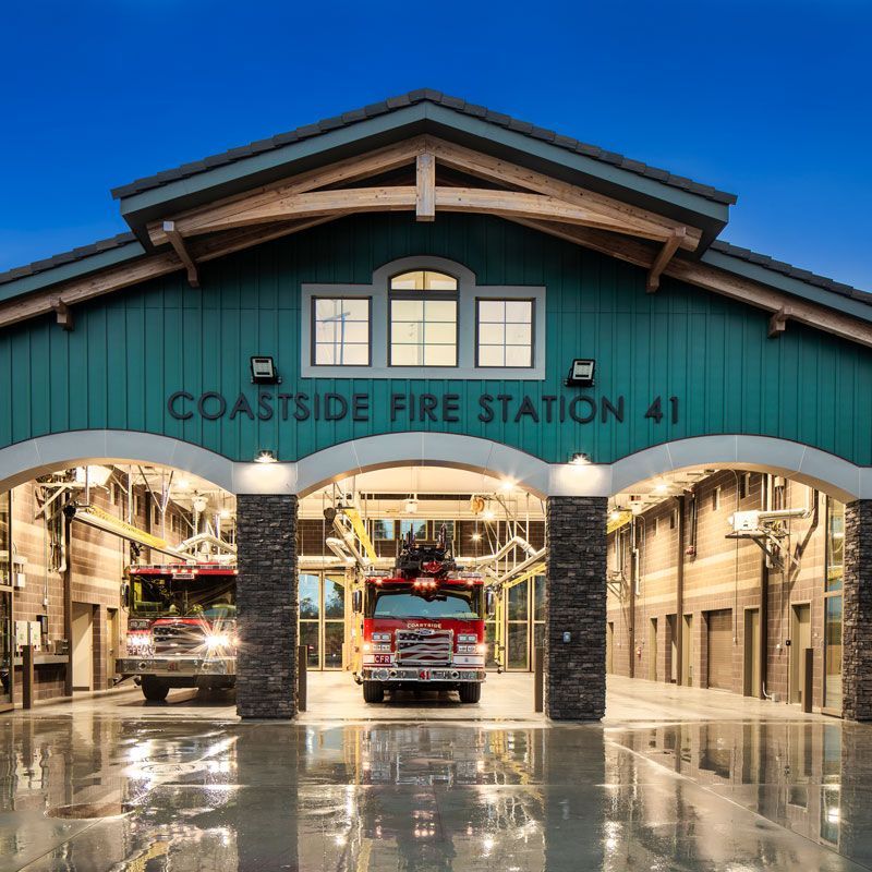 Coastside Fire Station 41 with fire trucks parked inside the open bays at dusk