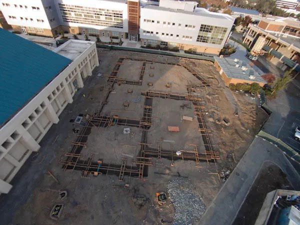 Aerial view of a construction site with foundation forms in a courtyard between buildings