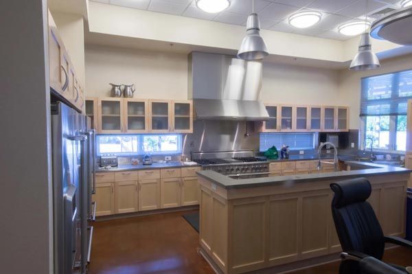 Bright kitchen with wood cabinets, island, stainless hood, and large windows