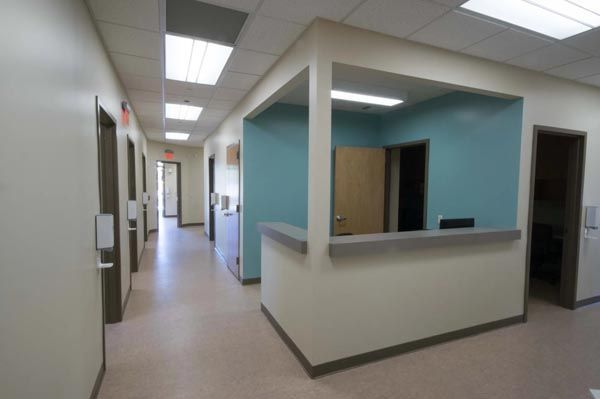 Empty hospital hallway with teal reception desk and fluorescent ceiling lights
