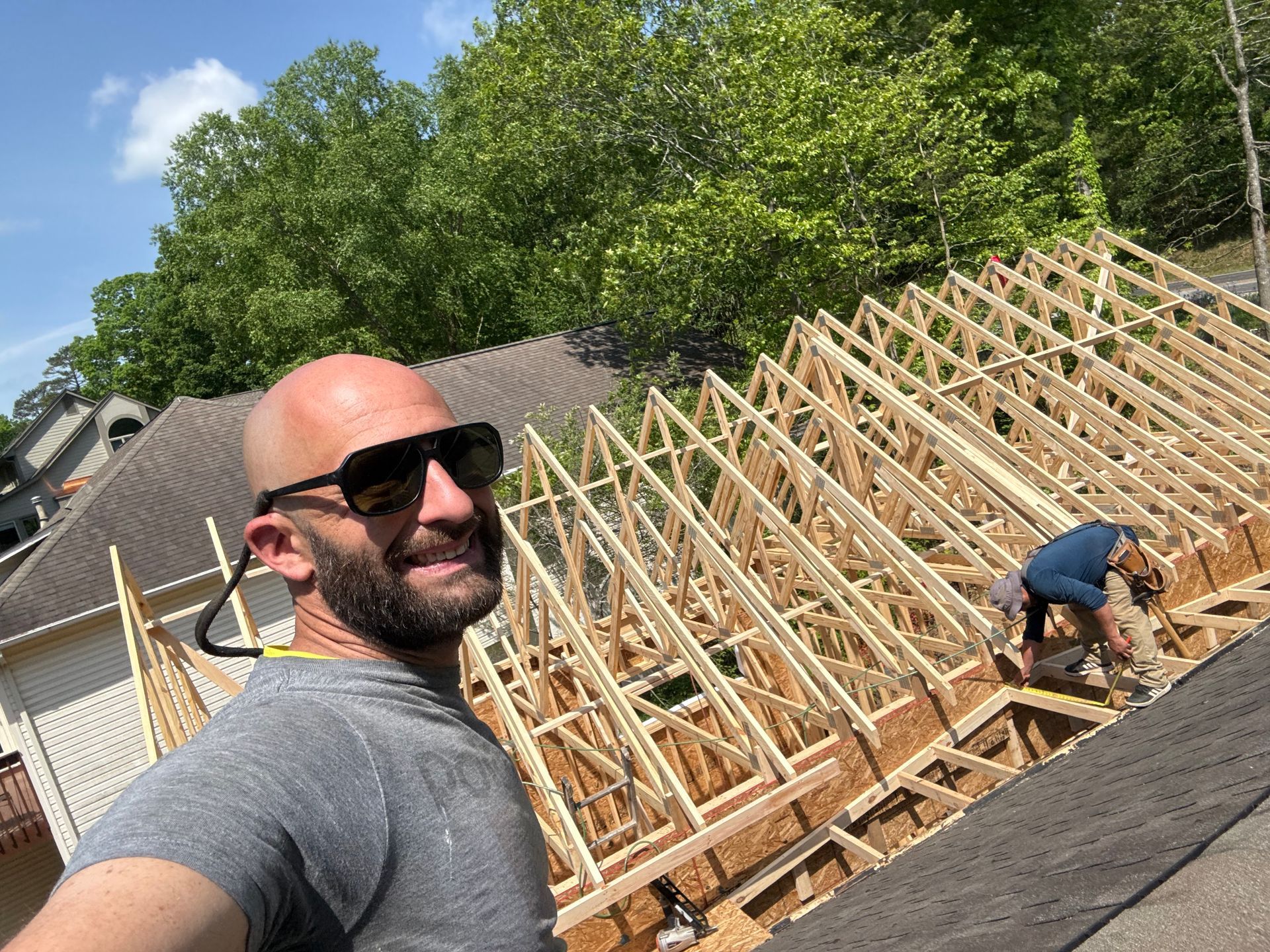 A man is standing on the roof of a house under construction.