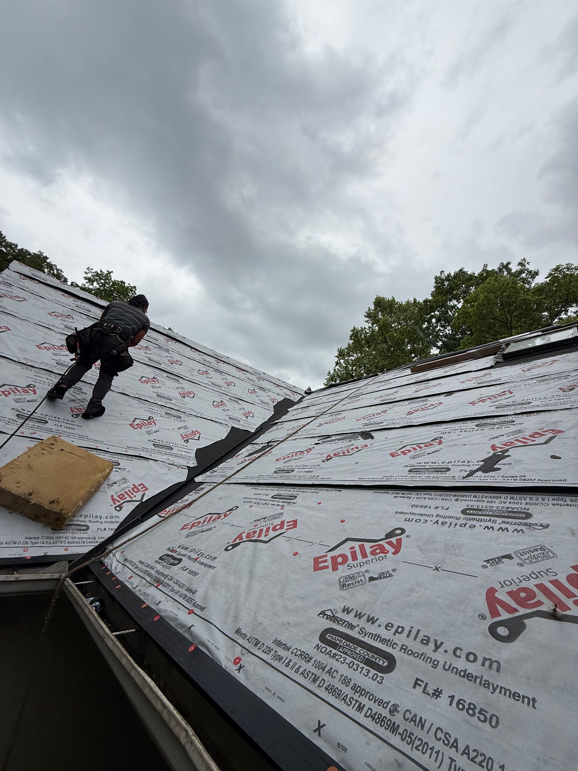 A man is standing on top of a roof with a box on it.