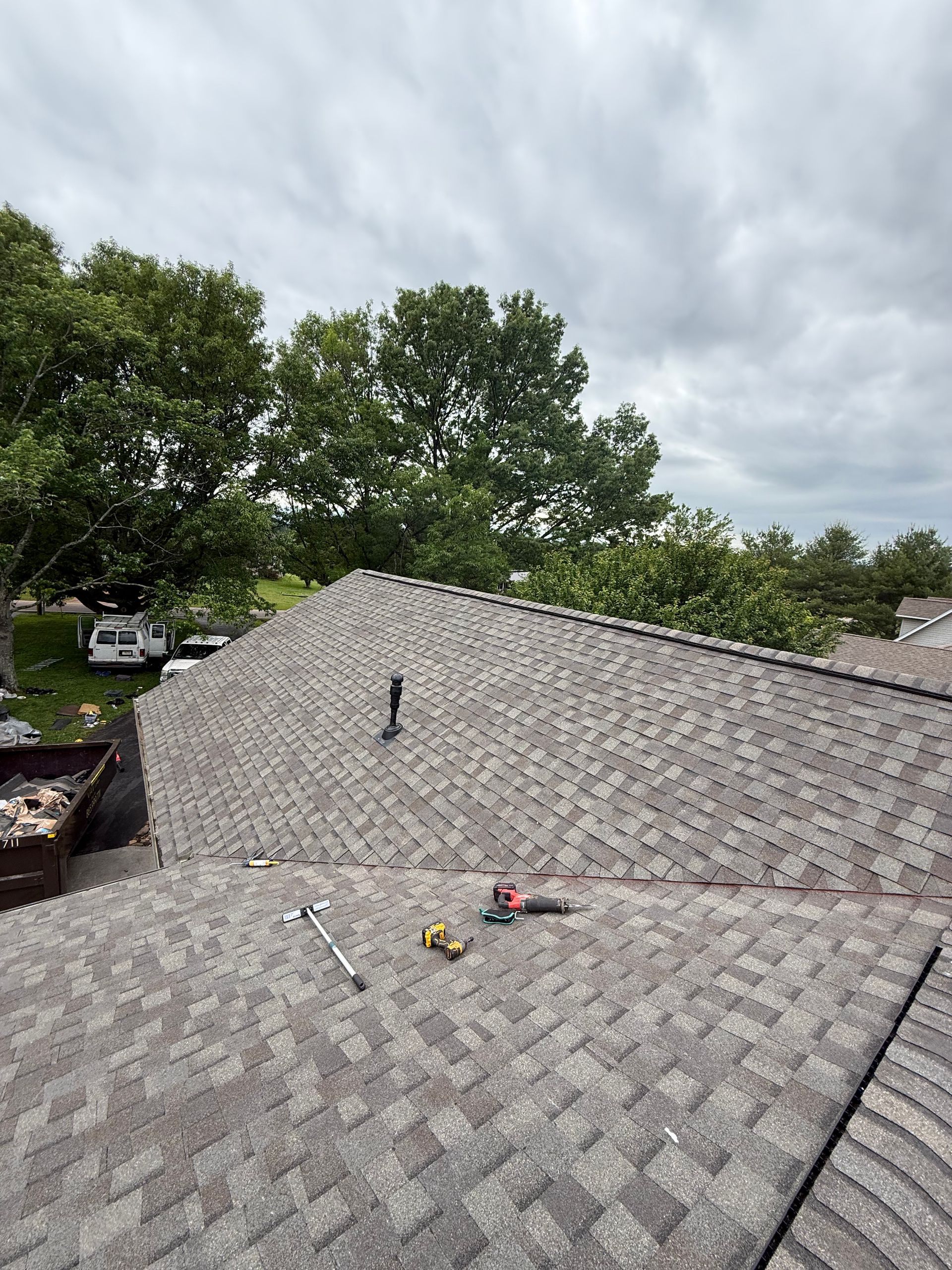A roof with a few tools on it and trees in the background.