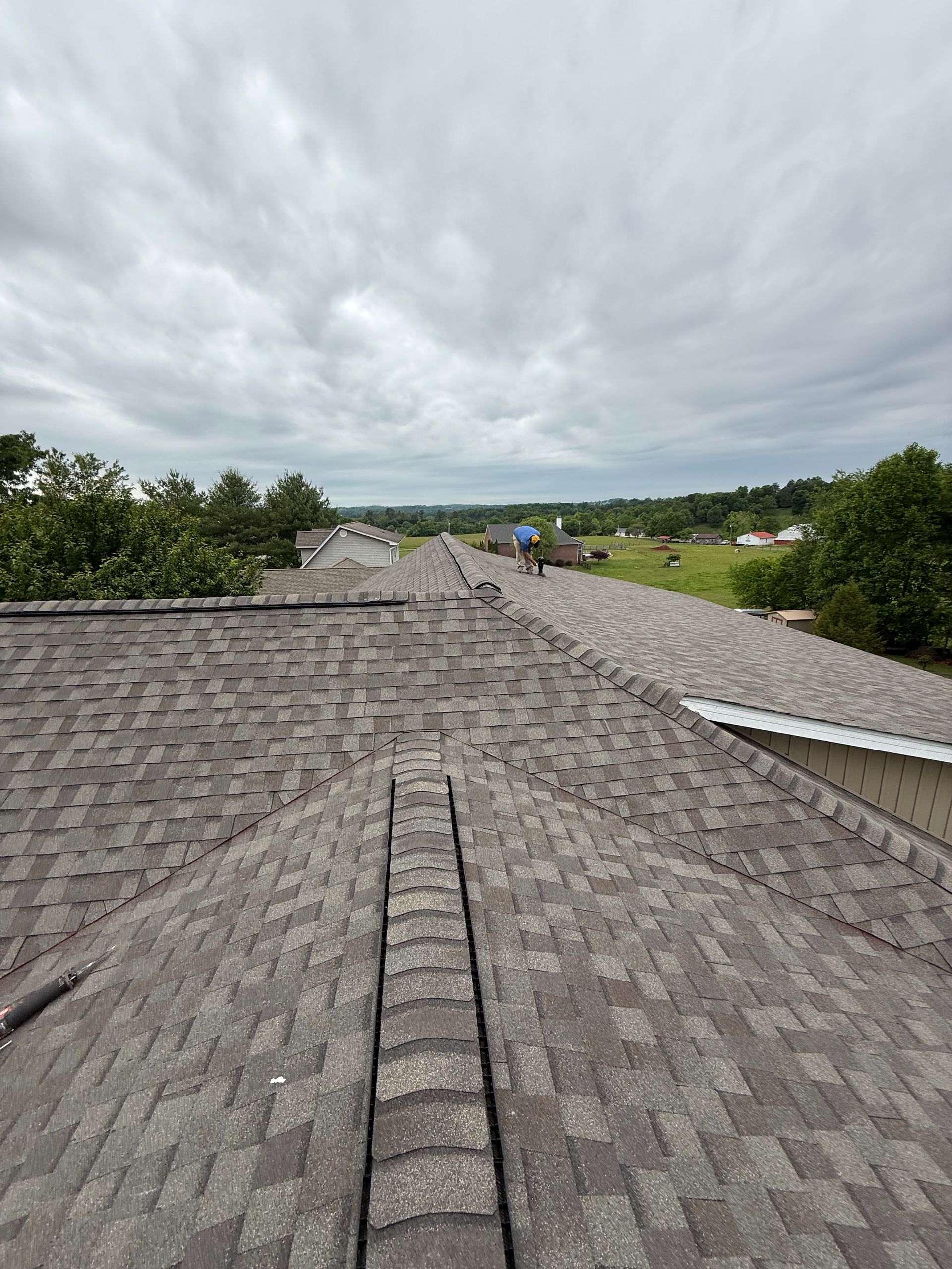 A roof with a ladder on it and a cloudy sky in the background.
