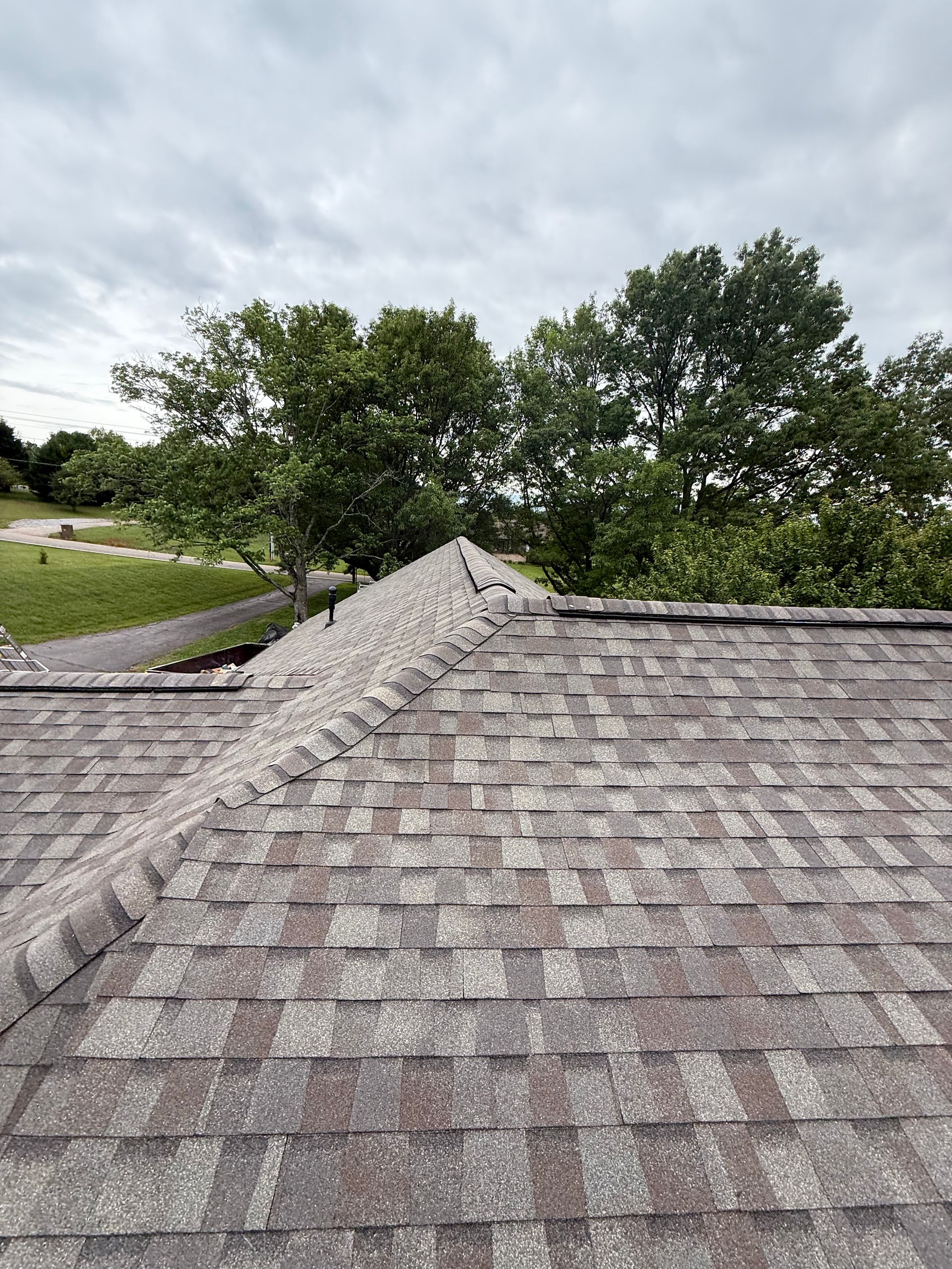 A roof with a lot of shingles on it and trees in the background.