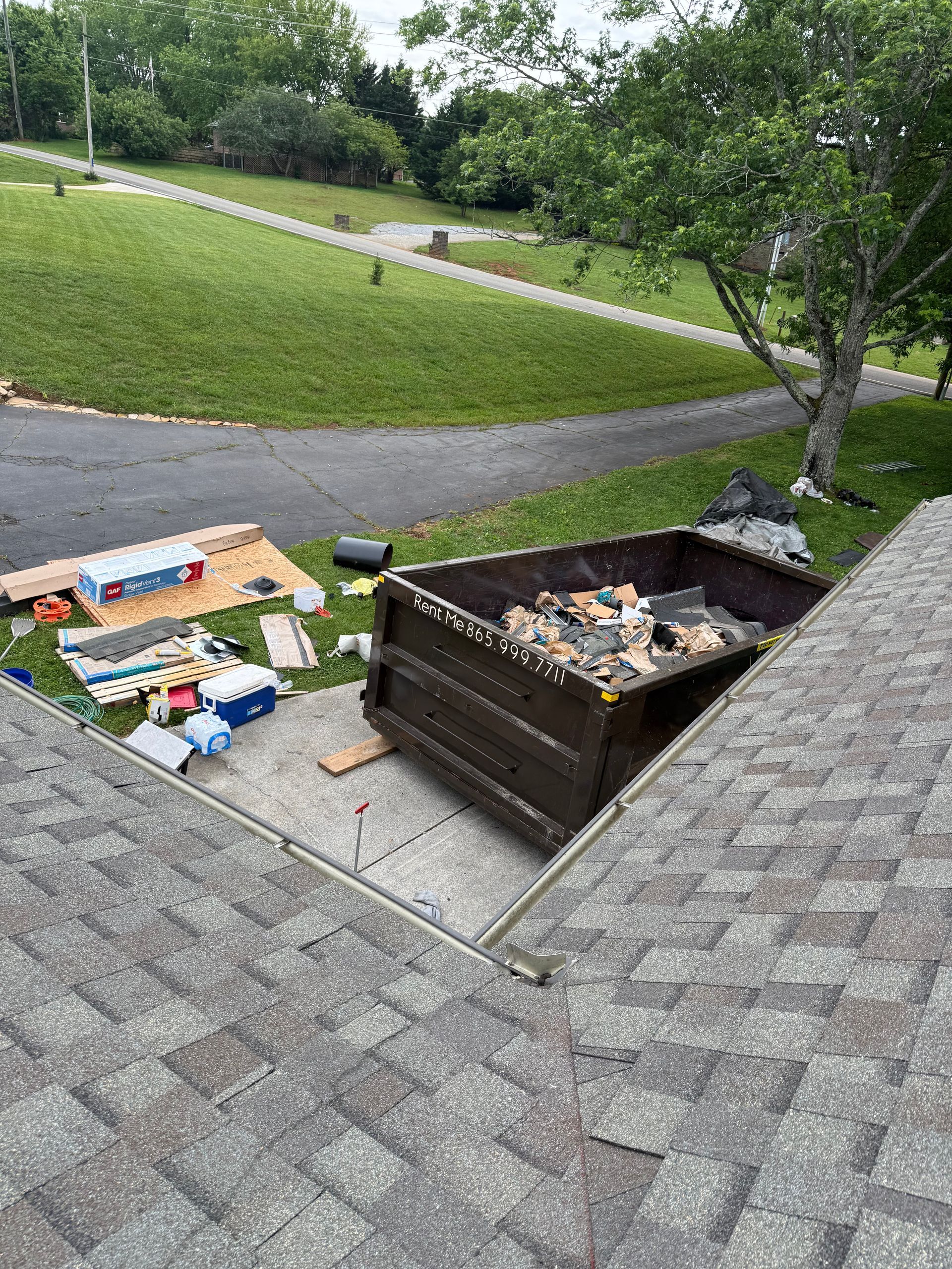 A dumpster is sitting on the roof of a house.
