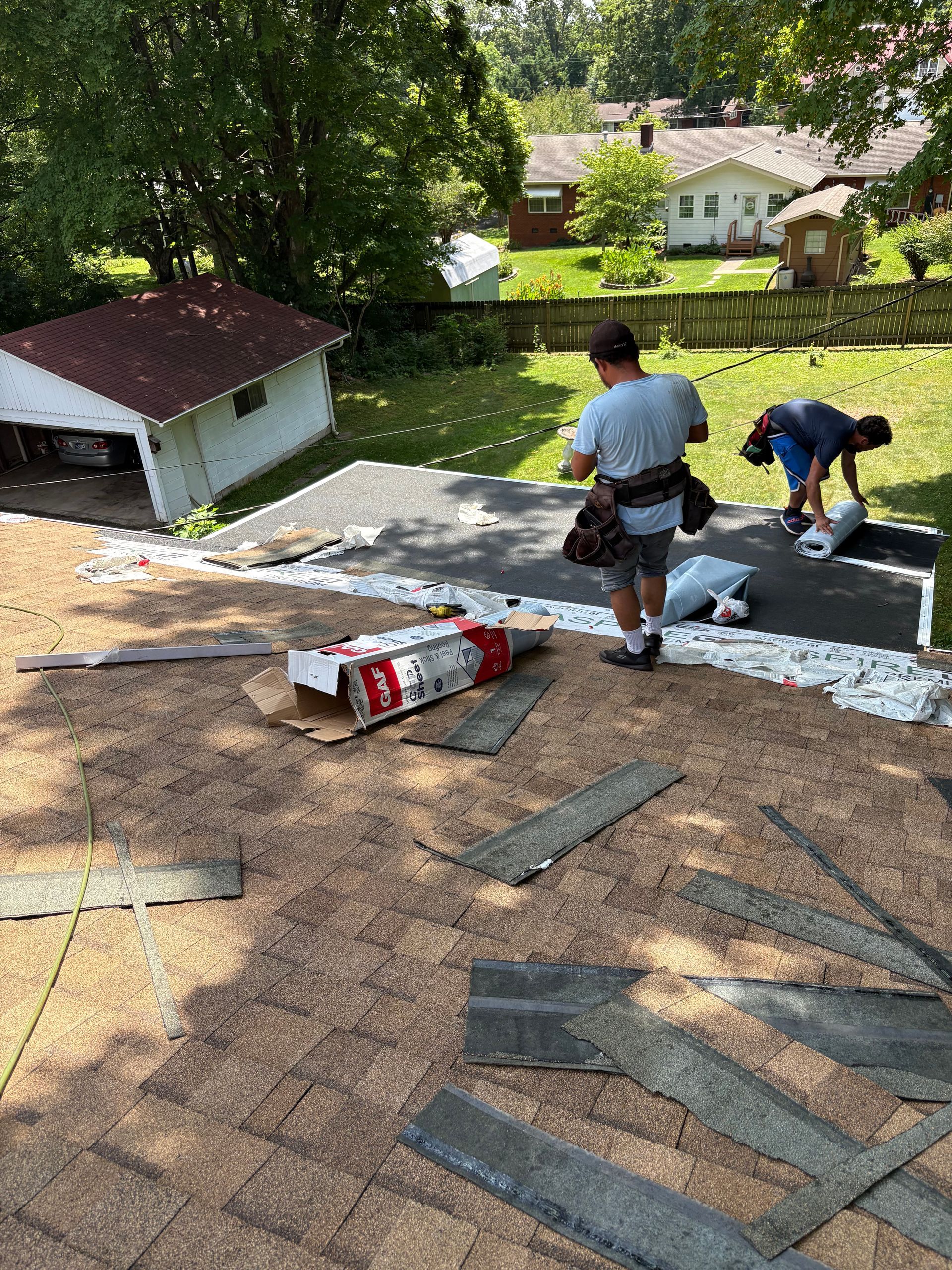 Two men are working on a roof of a house.